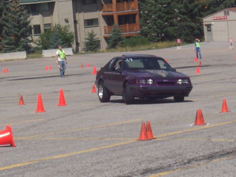 1972 Ford Ranchero - A purple coupe navigates a cone course on a paved lot, with a building in the background.