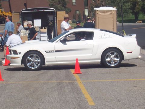 1972 Ford Ranchero - A white coupe with GT/CS badging is parked on asphalt, with people and a trailer in the background.