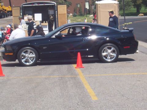 1972 Ford Ranchero - A black Ford Mustang GT is parked on asphalt with orange cones marking a spot.