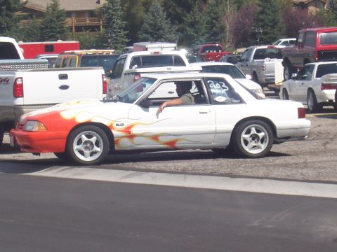 1972 Ford Ranchero - A white coupe with flame decals is parked among other vehicles in a lot.