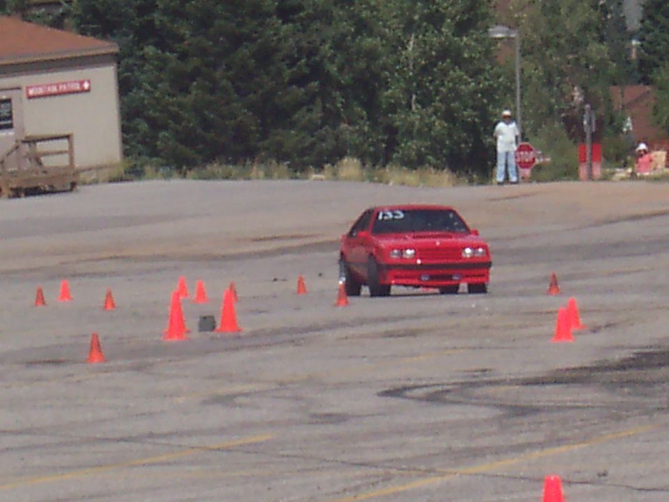 Red coupe with number 155 on windshield navigates a cone course