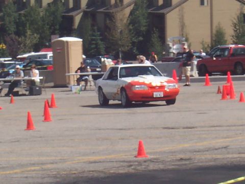 1972 Ford Ranchero - A white and orange Ford Mustang is seen on a paved lot with orange cones marking a course.