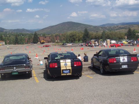 1972 Ford Ranchero - Several Ford Mustangs are parked in a lot, with cones set up for an event in the background.
