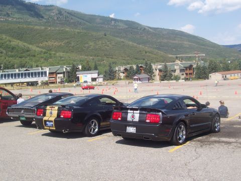 1972 Ford Ranchero - Several Ford Mustangs are parked in a lot with a mountain range in the background.