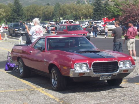 1972 Ford Ranchero - This red 1972 Ford Ranchero features a black hood stripe and chrome accents, seen at an outdoor event.