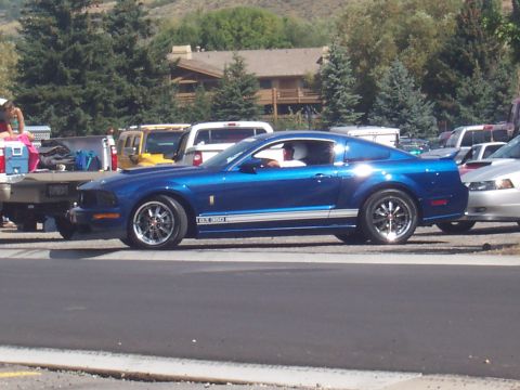 1972 Ford Ranchero - Blue 2007 Ford Mustang Shelby GT500 parked on a sunny day with other vehicles around.