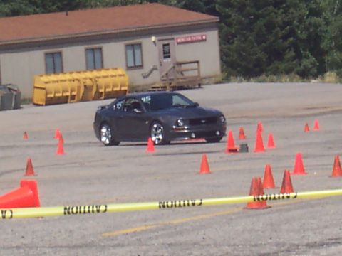 1972 Ford Ranchero - A dark gray Ford Mustang is navigating a course marked by orange cones and caution tape.