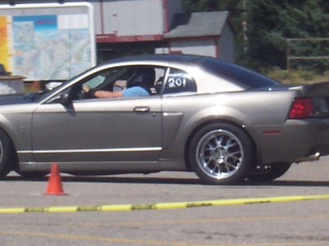 1972 Ford Ranchero - A gray coupe with a black roof and racing number 201 is visible from the side, with a driver wearing a helmet.