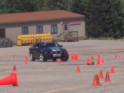 1972 Ford Ranchero - A black coupe with silver racing stripes navigates a cone course, indicating a timed event or training session.