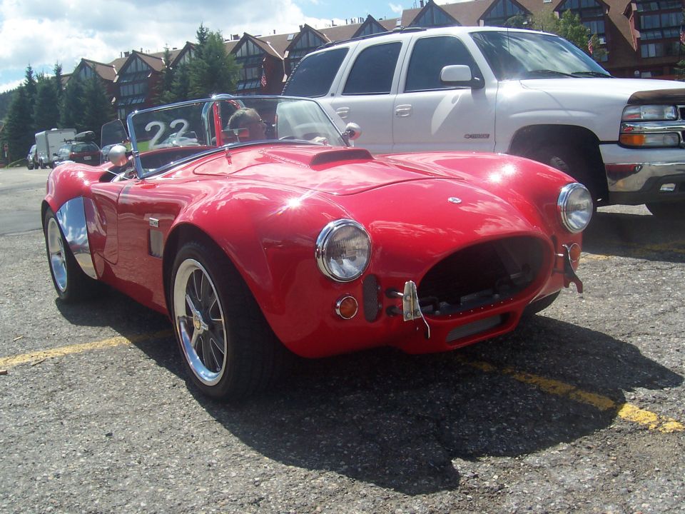 Red convertible sports car with racing number 22 on windshield, chrome accents, and a scoop on the hood
