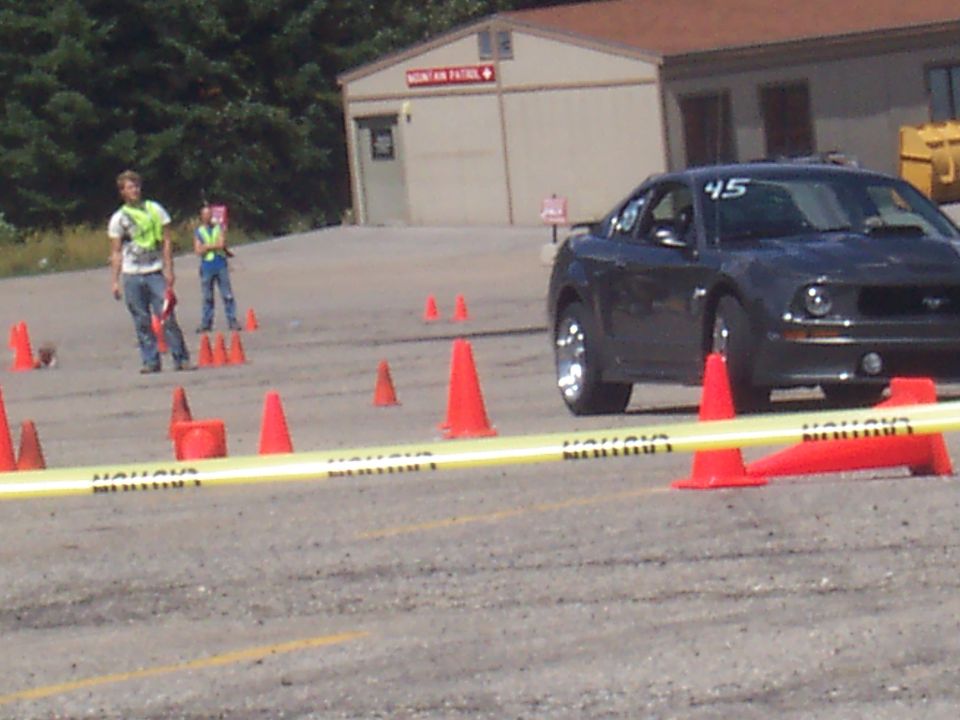 Dark gray Ford Mustang with number 45 on windshield, navigating a cone course