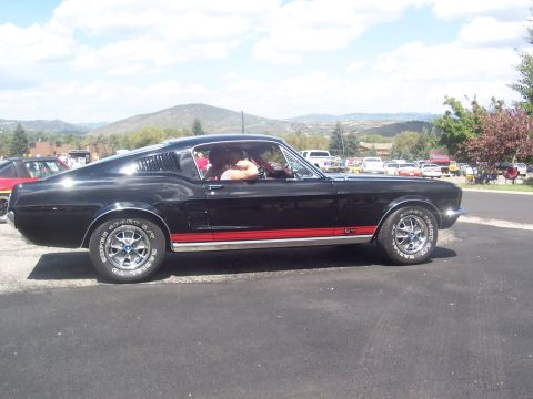 1972 Ford Ranchero - A black 1967 Ford Mustang Fastback is parked outdoors with other vehicles in the background.