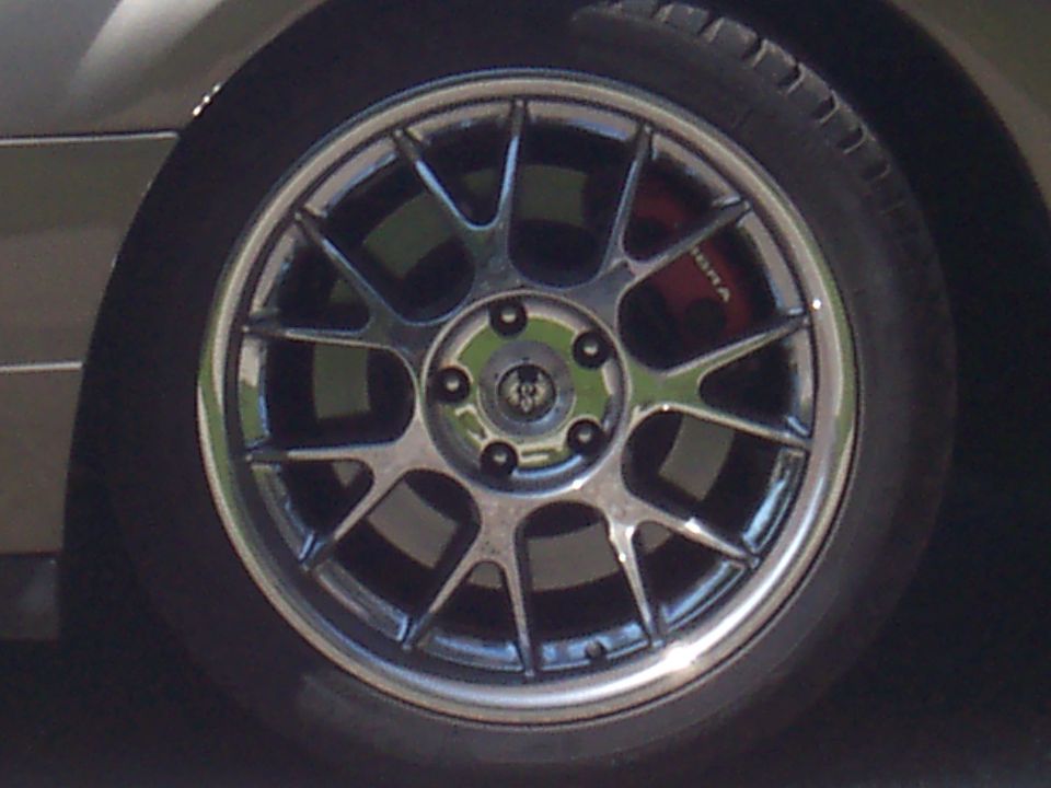 Close-up of a chrome multi-spoke wheel with a red brake caliper visible behind it