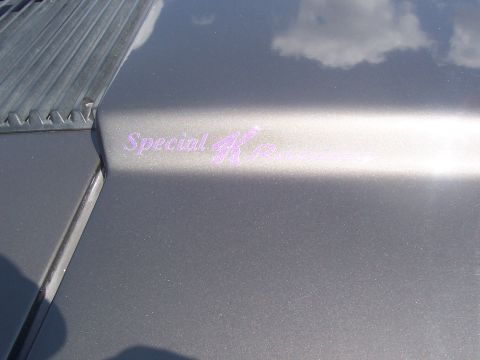 1972 Ford Ranchero - Close-up of a "Special K" emblem on the hood of a gray vehicle, with clouds reflected on the surface.