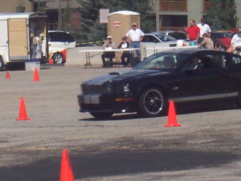 1972 Ford Ranchero - A black Ford Mustang with silver racing stripes is parked on a track with orange cones.