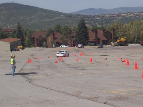 1972 Ford Ranchero - A white car is seen from the rear, maneuvering through a course marked by orange cones in a paved lot.