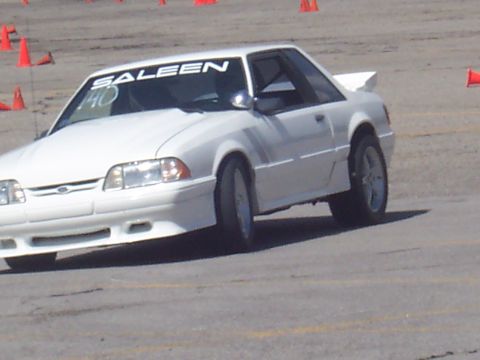 1972 Ford Ranchero - A white Saleen Mustang coupe is seen on a track with orange cones in the background.
