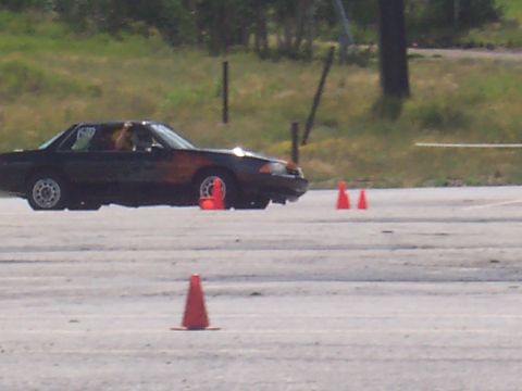 1972 Ford Ranchero - A dark coupe with orange accents navigates a course marked by traffic cones on a paved surface.