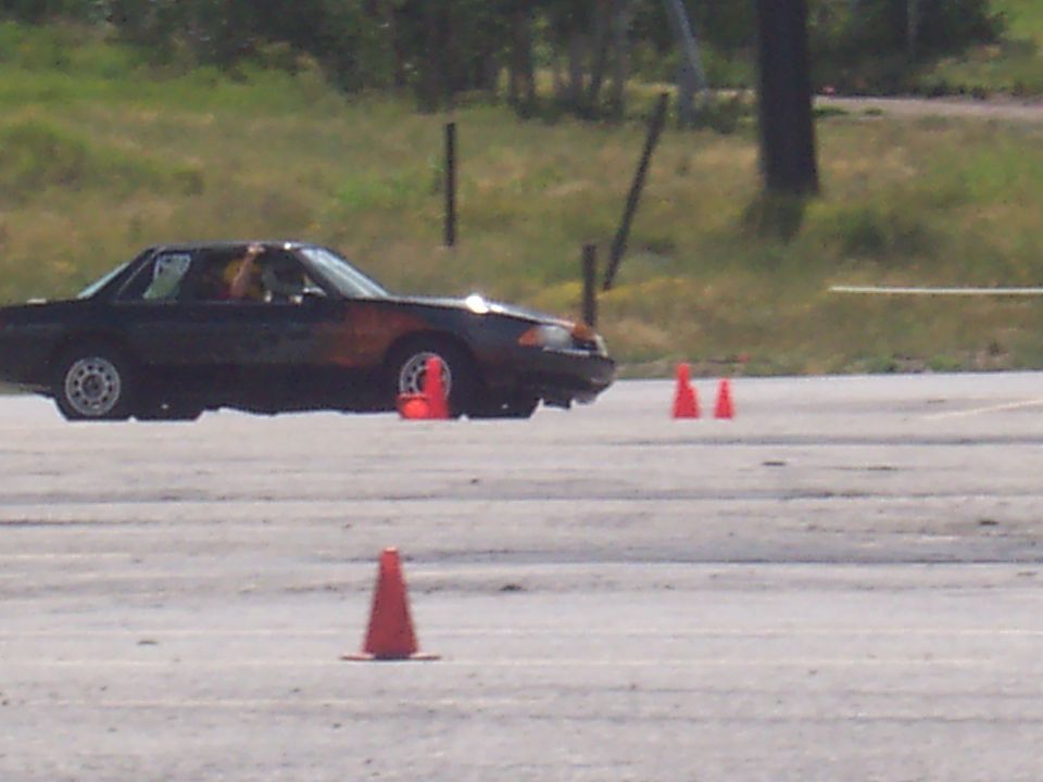 Dark coupe with orange accents on a race track, side view