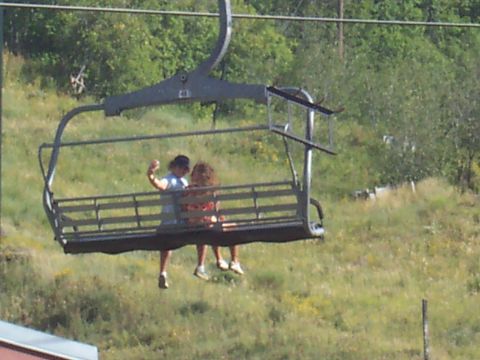1972 Ford Ranchero - Two people ride a ski lift over a grassy hillside.