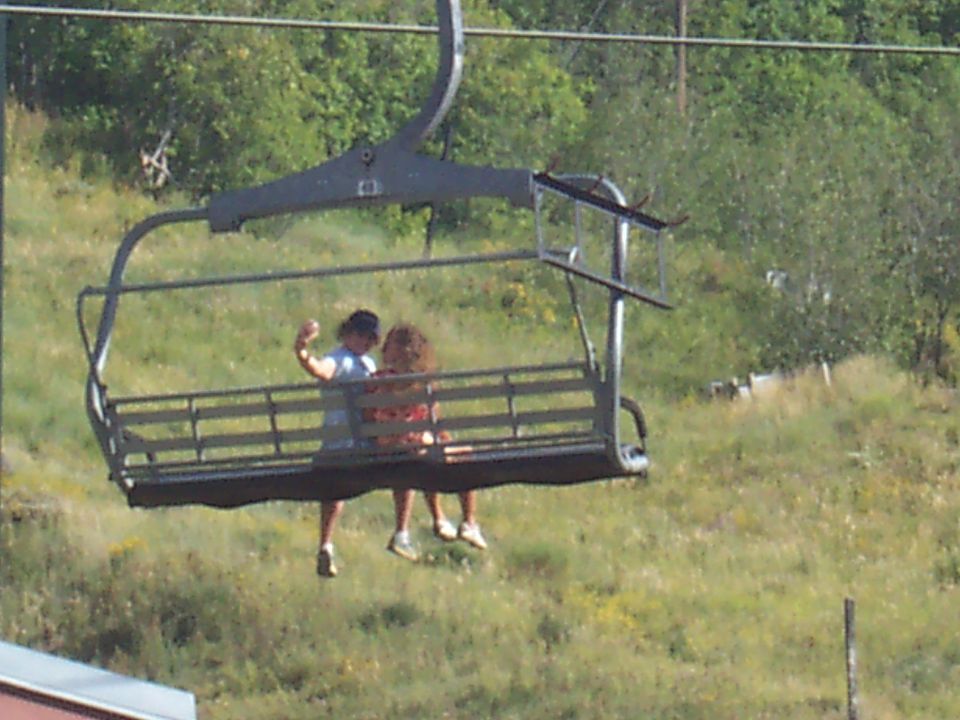 Ski lift carrying two people up a grassy slope