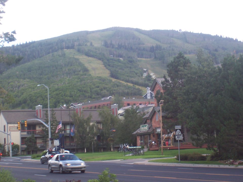 Mountain town with buildings and trees in foreground, ski slopes visible on mountain