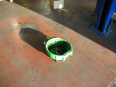 1992 Ford Crown Victoria - A green oil drain pan sits on a red concrete floor, catching dark fluid.
