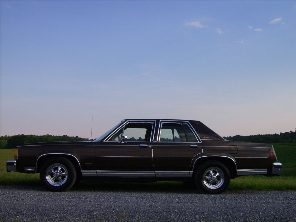 Dark brown Ford LTD Crown Victoria four-door sedan in side profile at dusk