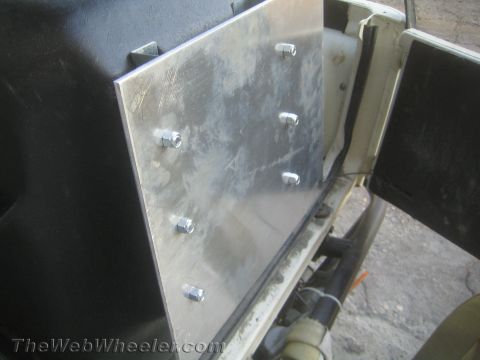 1987 Suzuki Samurai - A metal plate is bolted onto a black interior panel, showing a modification or repair.