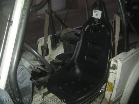 1987 Suzuki Samurai - The interior of a vehicle shows a new racing seat installed, with a roll cage present for safety.