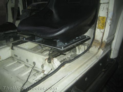 1987 Suzuki Samurai - Interior view of a vehicle showing a black bucket seat mounted on a fabricated aluminum seat base bracket over the floor pan. The white pai…