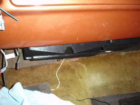 1977 Ford F-150 - Close-up of an under-dash speaker enclosure in an older vehicle with orange paint and carpeted floor.