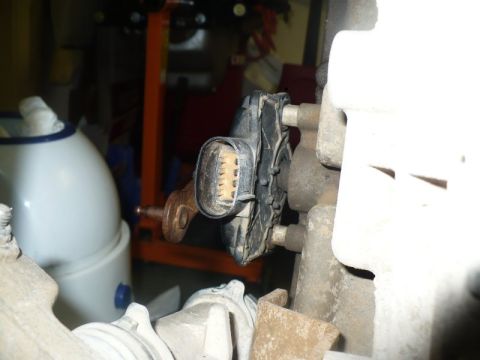 1995 Ford Bronco - An electrical connector with a tan multi-pin socket is attached to a metal component in this close-up view.