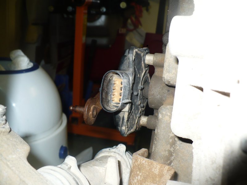 Close-up of a black electrical connector with a tan multi-pin socket attached to a metal component