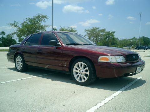 2004 Ford Crown Victoria - Maroon 2004 Ford Crown Victoria parked in a lot under a partly cloudy sky.
