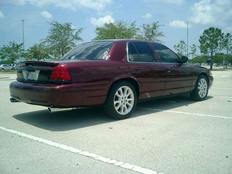 2004 Ford Crown Victoria - Maroon 2004 Ford Crown Victoria with white wheels and a spoiler parked in a lot.