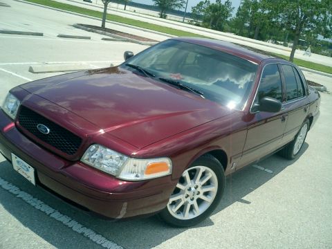 2004 Ford Crown Victoria - A maroon 2004 Ford Crown Victoria is parked in a lot on a sunny day.