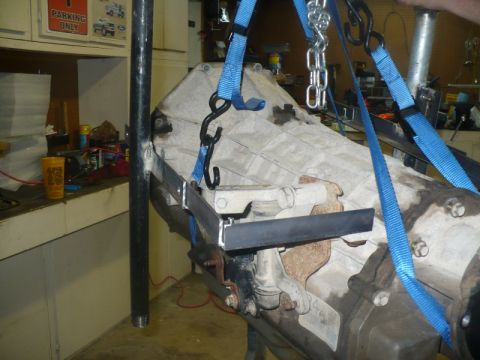 1995 Ford Bronco - Transmission assembly suspended by straps and chains, likely for removal or installation.