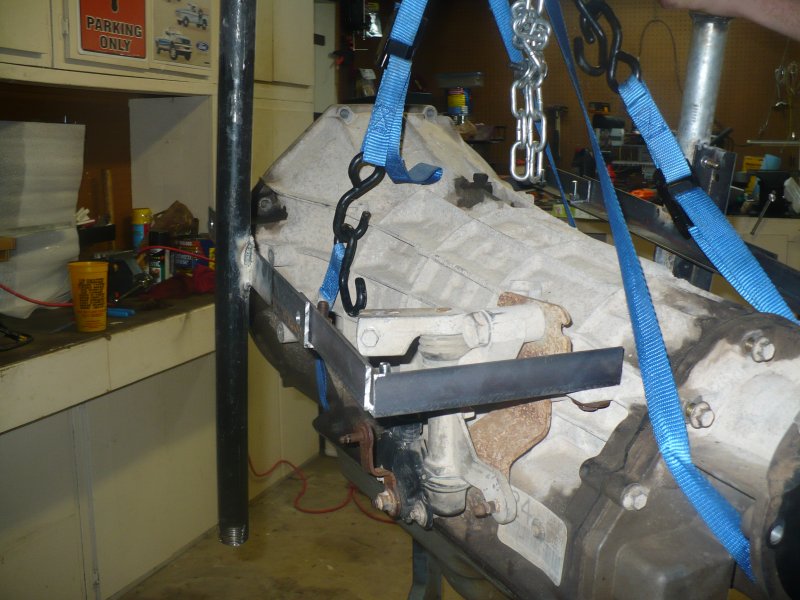 Transmission being lifted by straps and chains