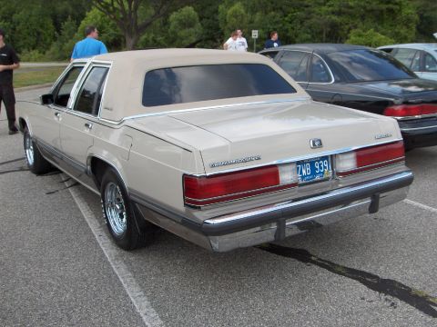 1988 Mercury Grand Marquis - Rear view of a tan 1988 Mercury Grand Marquis sedan with chrome wheels and a vinyl top.