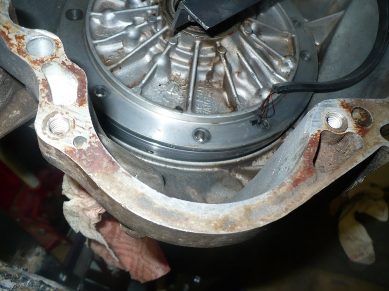 close-up of a rusty metal bracket attached to a circular metal component with wires