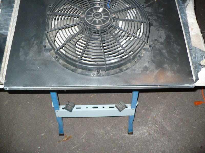 Electric radiator fan mounted on a metal shroud, supported by a blue and gray stand