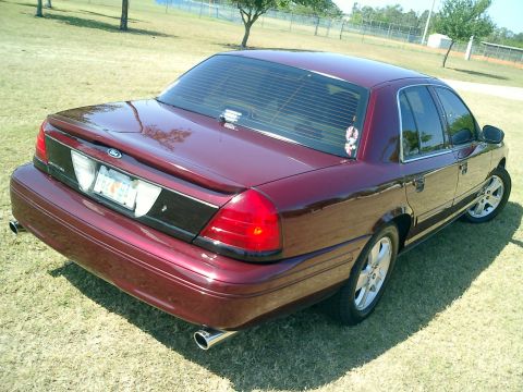 2004 Ford Crown Victoria - A maroon Ford Crown Victoria is shown from the rear quarter angle, parked on a grassy area.
