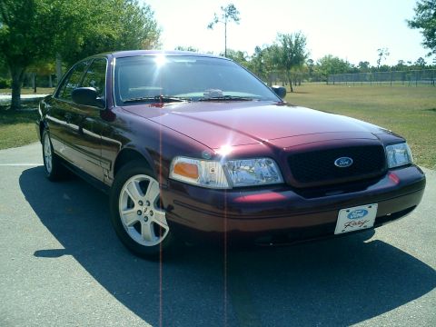 2004 Ford Crown Victoria - A maroon 2004 Ford Crown Victoria is parked outside on a sunny day, showing its front quarter profile and a Ford Racing license plate.