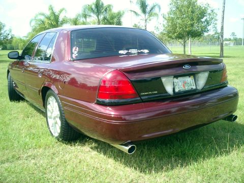 2004 Ford Crown Victoria - Rear view of a maroon 2004 Ford Crown Victoria parked on grass with trees in the background.