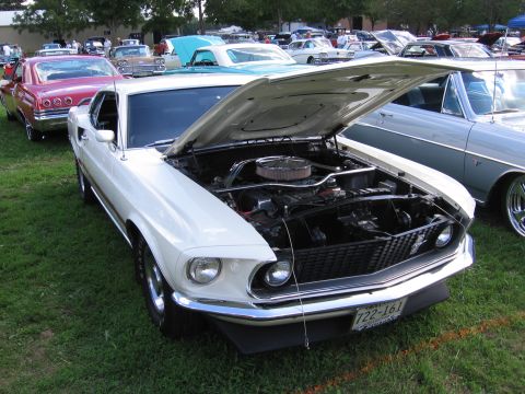 1989 Ford Mustang - A white 1969 Ford Mustang is displayed with its hood open at an outdoor car show.