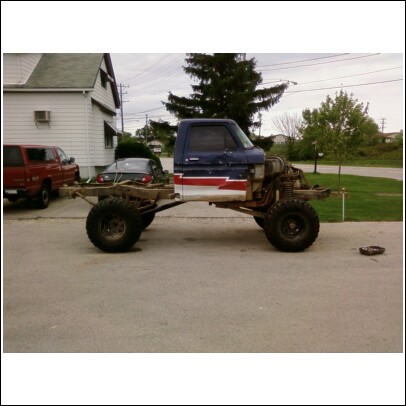 1977 Ford F-150 - Custom pickup truck chassis with cab, painted with red and white stripes. A red truck is parked nearby.