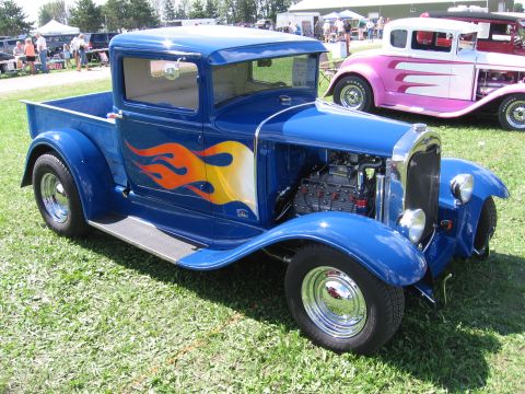 1989 Ford Mustang - A blue hot rod pickup truck with flame decals is parked on grass, with another car in the background.