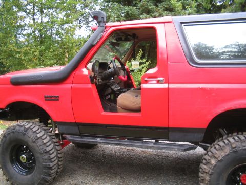 1989 Ford Bronco - Side view of a red 1989 Ford Bronco modified for off-roading, showing the interior and snorkel.