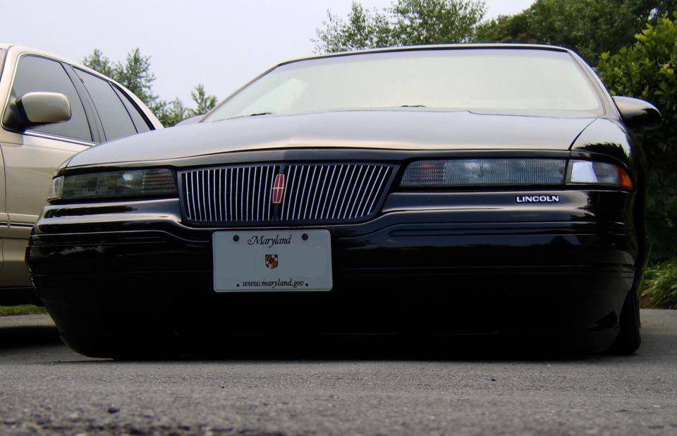 Front end of a lowered black Lincoln Mark VIII showing grille and badge